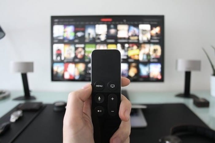 Hand holding remote control in front of a screen