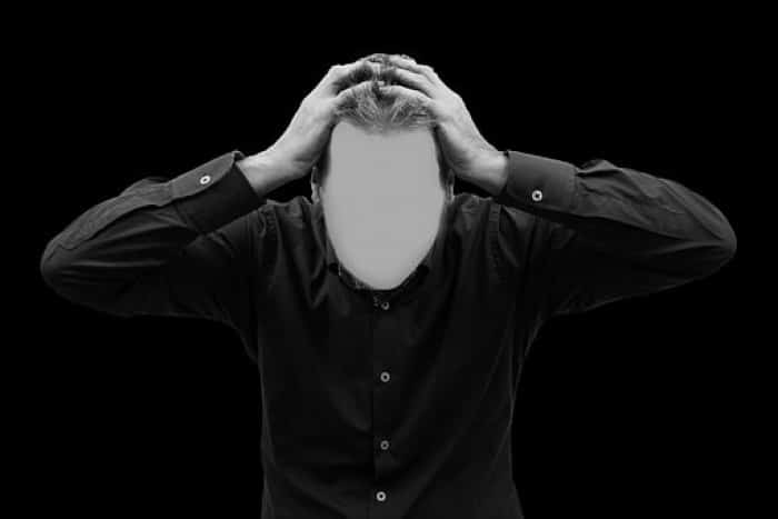 Man holding hands on head with blurred out face